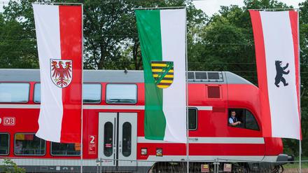 Ein Regionalexpress der Deutschen Bahn fährt am 30.05.2016 in Baruth (Brandenburg) an den Landesfahnen von Brandenburg, Sachsen und Berlin vorbei. 