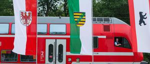 Ein Regionalexpress der Deutschen Bahn fährt am 30.05.2016 in Baruth (Brandenburg) an den Landesfahnen von Brandenburg, Sachsen und Berlin vorbei.