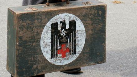 Der DRK-Adler auf dem Koffer eines Mannes, der am Sonntag in Colmnitz (Sachsen) bei einem historischen Festumzug zum "Schul- und Heimatfest" als Wehrmachtssoldat verkleidet mitläuft. Die Polizei ermittelt wegen des Verwendens von Kennzeichen verfassungswidriger Organisationen.
