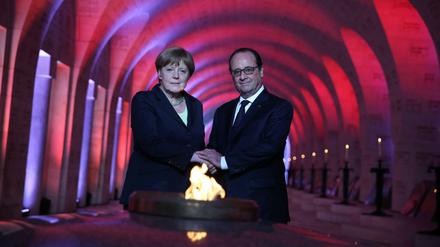Der französische Präsident Francois Hollande und Bundeskanzlerin Angela Merkel (CDU) entzünden gemeinsam die Flamme in der Nationalnekropole Douaumont bei Verdun.