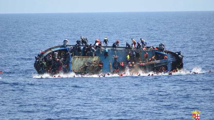 Ein kenterndes Flüchtlingsboot vor der Rettung durch die italienische Marine.