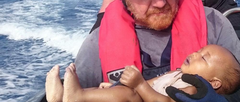 Ein deutscher Retter der Organisation Sea-Watch hält ein ertrunkenes Flüchtlingsbaby in den Armen.