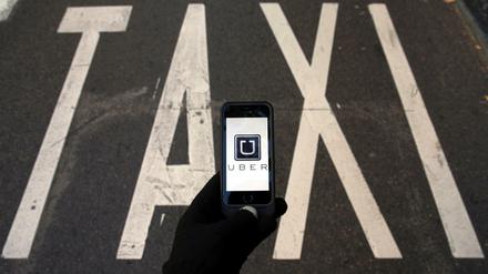 Das Logo von Uber auf einem Smartphone vor einer Taxi-Spur.