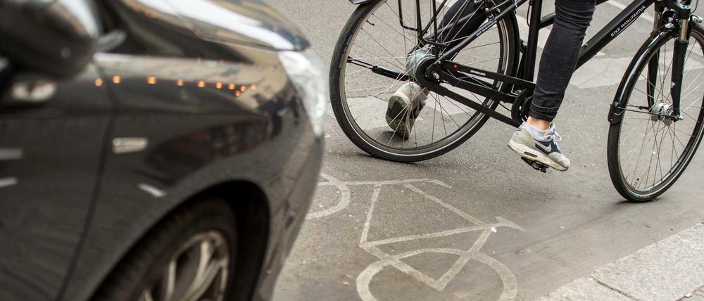 Eine Radfahrerin umfährt ein auf dem Radweg stehendes Auto.