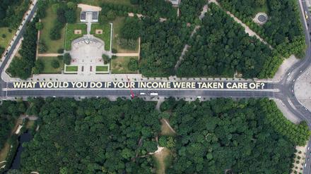 "WHAT WOULD YOU DO IF YOUR INCOME WERE TAKEN CARE OF?" steht auf dem riesigen Plakat auf der Straße des 17. Juni zwischen der Siegessäule und dem Brandenburger Tor in Berlin. 