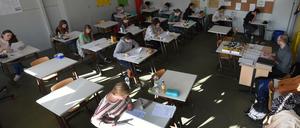Ein Lehrer sitzt an seinem Pult vor der Klasse.