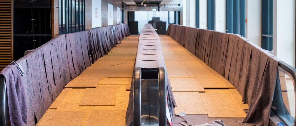 Geschützt mit Decken und Brettern vor Verschmutzung durch die laufenden Bauarbeiten sind zwei Laufbänder am 15.10.2015 im Terminalgebäude des Hauptstadtflughafens Berlin Brandenburg Willy Brandt (BER).