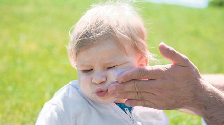 Aua, Papa! Sonnencreme ist nicht beliebt, dennoch für Kinder im Sommer ein Muss. Das oberste Gebot heißt aber: Schatten suchen! 