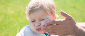 Aua, Papa! Sonnencreme ist nicht beliebt, dennoch für Kinder im Sommer ein Muss. Das oberste Gebot heißt aber: Schatten suchen!