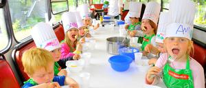 Der Kochbus, ein zu einer Küche umgebauter Verkehrsbus, kommt in die Kitas - wie hier im Bild nach Tempelhof. Die Kinder lernen etwas zu gesunder Ernährung und schneiden und kochen die Mahlzeiten selbst.