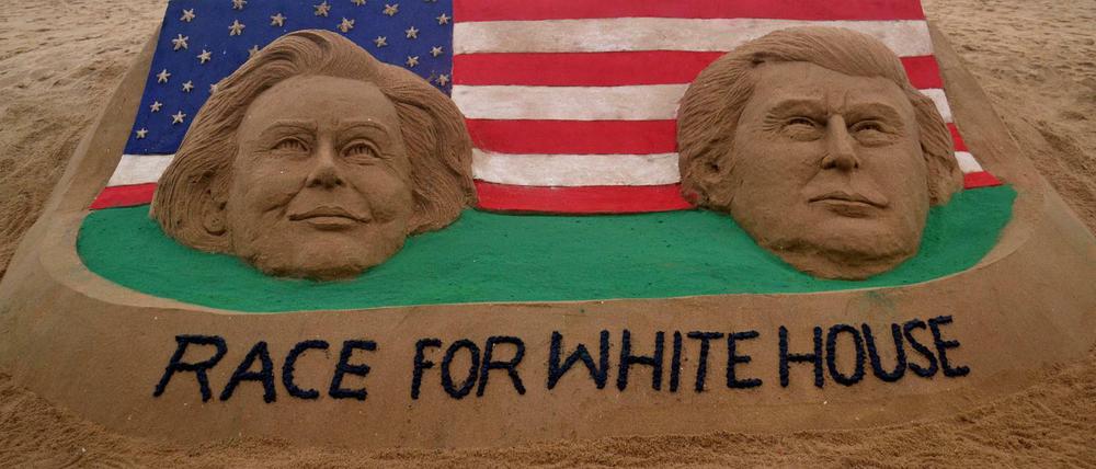 Die beiden Top-Kandidaten bei Einzug in das Weiße Haus: Hillary Clinton und Donald Trump als Köpfe in einer Sandburg.