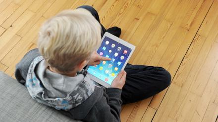 Ein Jugendlicher tippt auf seinem iPad auf das facebook-icon. 