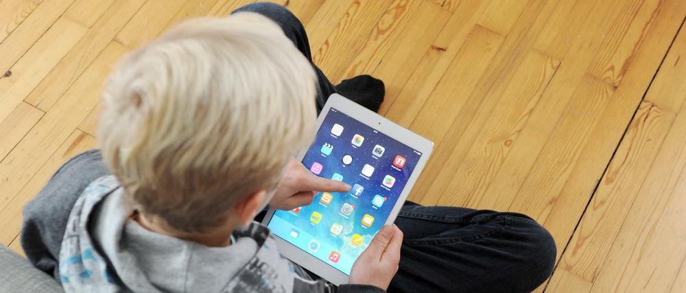 Ein Jugendlicher tippt auf seinem iPad auf das facebook-icon. 