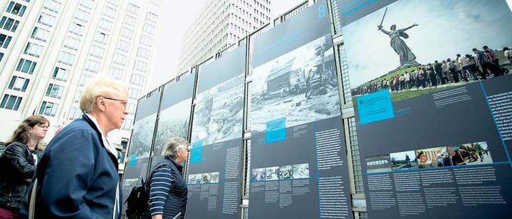 Menschen stehen vor Plakatwänden einer Freiluftausstellung und lesen die Texte.