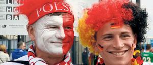 Zwei Männer, einer in den polnischen Farben geschminkt, einer in den deutschen, blicken lachend in die Kamera.