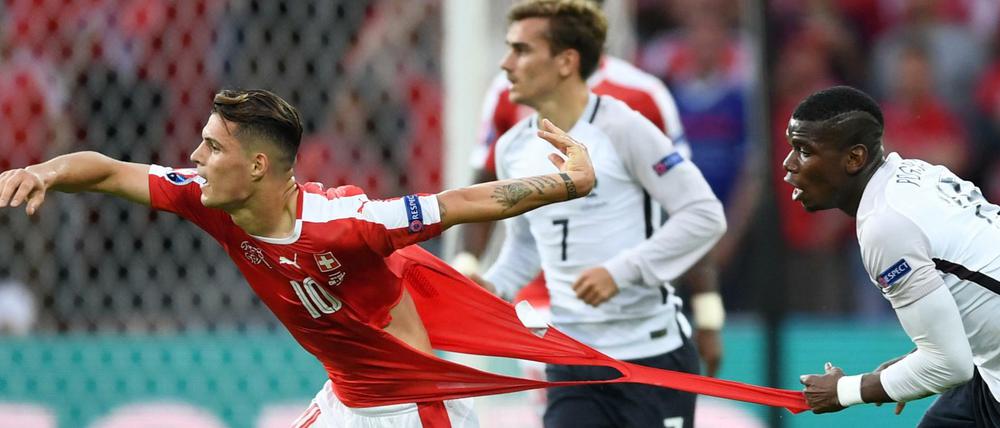 Der Franzose Paul Pogba (links) versucht den Schweizer Granit Xhaka am Trikot festzuhalten und zerreißt es dabei. 