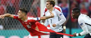 Der Franzose Paul Pogba (links) versucht den Schweizer Granit Xhaka am Trikot festzuhalten und zerreißt es dabei. 