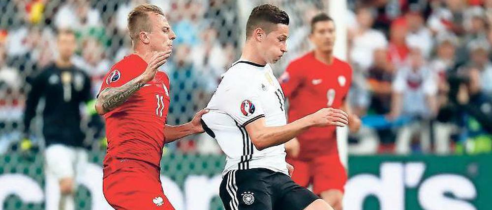 Reißprobe. Das deutsche Trikot ist schwer zu fassen. Auch Polens Grosicki hatte bei Draxler Probleme.