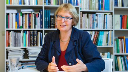 Eine Frau sitzt lächelnd vor einer Bücherwand.