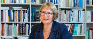 Eine Frau sitzt lächelnd vor einer Bücherwand.