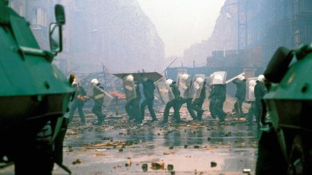 Polizisten schützen sich mit Schilden vor Steinwürfen während der Räumung besetzter Hauser in der Mainzer Straße in Friedrichshain 1990.