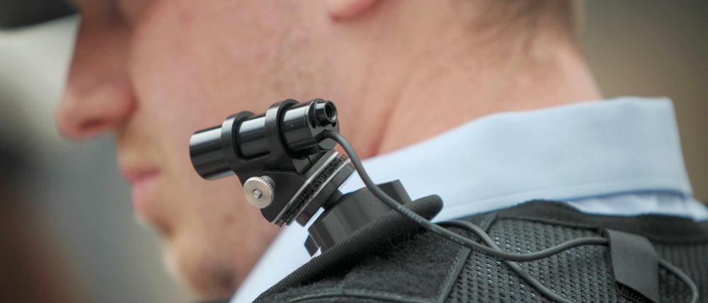Ein Polizist trägt eine mobile Miniatur-Videokamera auf seiner Schulter.
