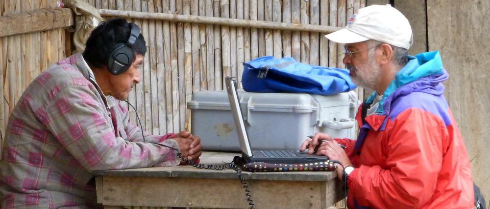 Hörtest. Das Foto zeigt wie ein Wissenschaftler einem Mitglied des am Amazonas lebenden Tsimane-Volkes westliche Musik über vom Laptop über Kopfhörer vorspielt.