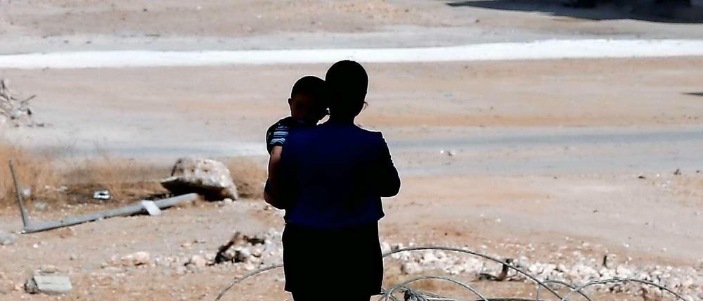 Eine syrische Frau mit ihrem Kind vor den Trümmern von Kobane.