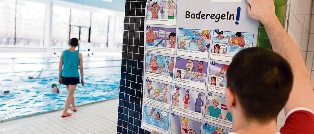 Ein Bademeister hängt am 08.02.2016 in der Schwimmhalle Fischerinsel in Berlin Plakate mit einer Darstellung der Baderegeln der Berliner Bäderbetriebe im Comic-Stil auf.