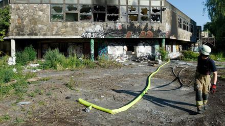 Ein Feuerwehrmann zieht Löschschläuche aus dem Gebäude. 