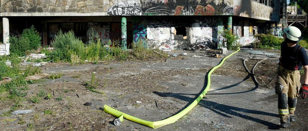 Ein Feuerwehrmann zieht Löschschläuche aus dem Gebäude.