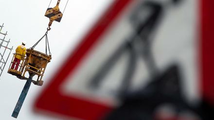 Ein Arbeiter steht auf einem Betonfüller, der an einem Baukran hängt.