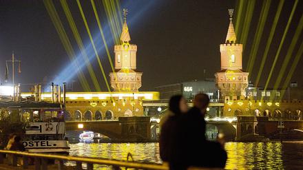 Ein Paar vor der angeleuchteten Oberbaumbrücke. 