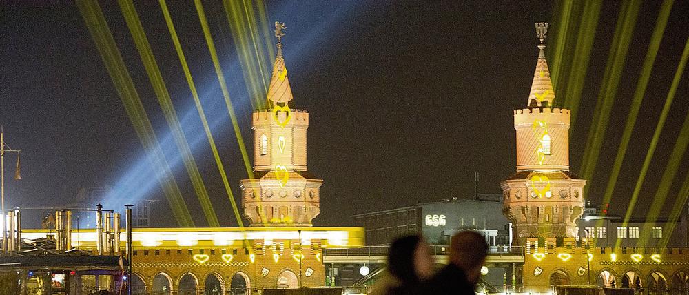 Ein Paar vor der angeleuchteten Oberbaumbrücke. 