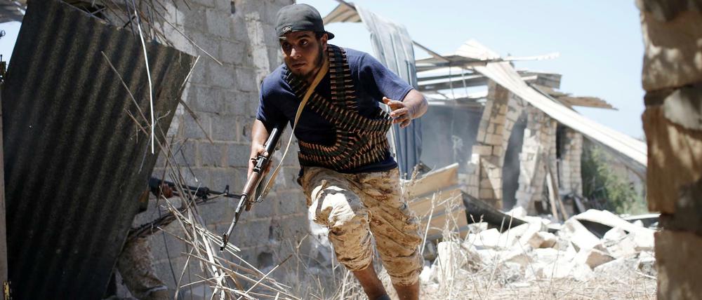 Ein Kämpfer der libyschen Streitkräfte sucht im Kampf um die vom IS gehaltene Stadt Sirte Schutz.