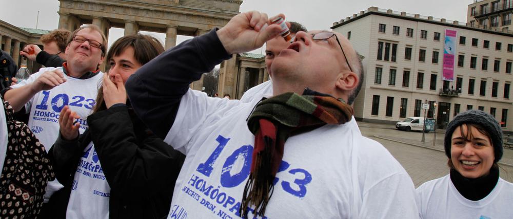 Runter damit! Anti-Homöopathie-Aktivisten ziehen sich vor dem Brandenburger Tor eine „Überdosis“ Globuli rein.