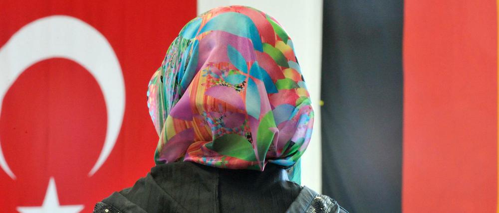 Eine Frau sitzt auf diesem Archivfoto in der DITIB-Moschee im hessischen Friedberg vor einer türkischen und einer deutschen Fahne.