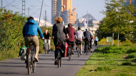 Zahlreiche Radfahrer fahren in Berlin im Sonnenschein durch den Park am Gleisdreieck in Richtung Potsdamer Platz.