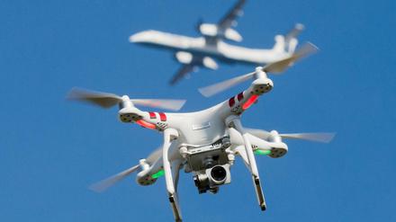 Eine private Drohne fliegt über einem Garten bei Breitscheid. In Entfernung ist ein Flugzeug beim Anflug auf den Flughafen Düsseldorf zu sehen.