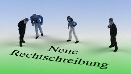 Nachdenkliche Figuren stolpern über die neue Rechtschreibung.