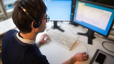 Ein Mann sitzt an seinem Arbeitsplatz vor einem Computerbildschirm. 