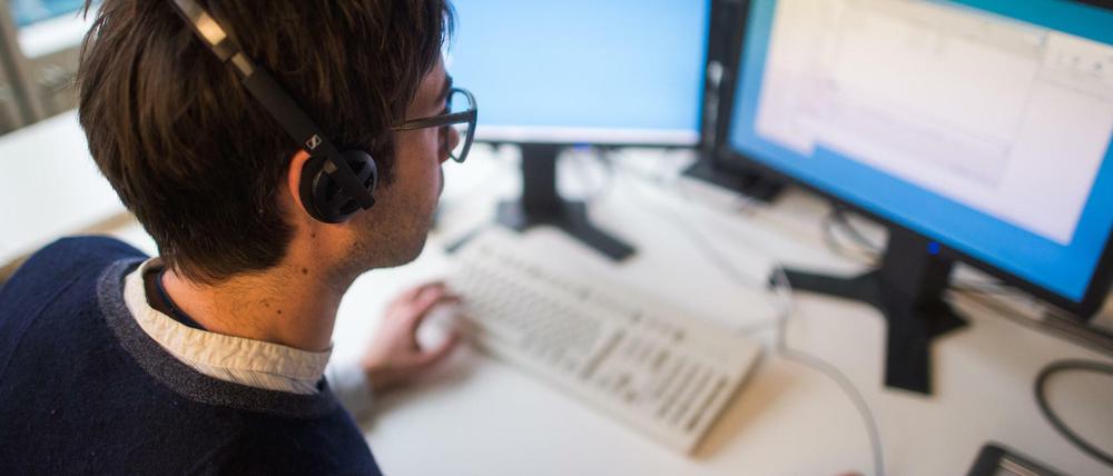 Ein Mann sitzt an seinem Arbeitsplatz vor einem Computerbildschirm.