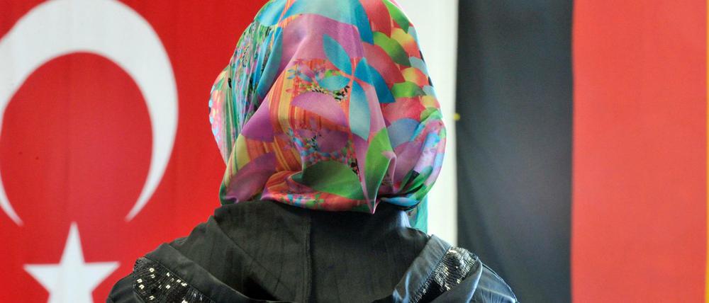 Eine Frau sitzt in der Ditib-Moschee im hessischen Friedberg vor einer türkischen und einer deutschen Fahne. 
