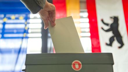 Eine Hand wirft in Berlin bei der Stimmabgabe zur Bundestagswahl einen Stimmzettel in eine Wahlurne. 