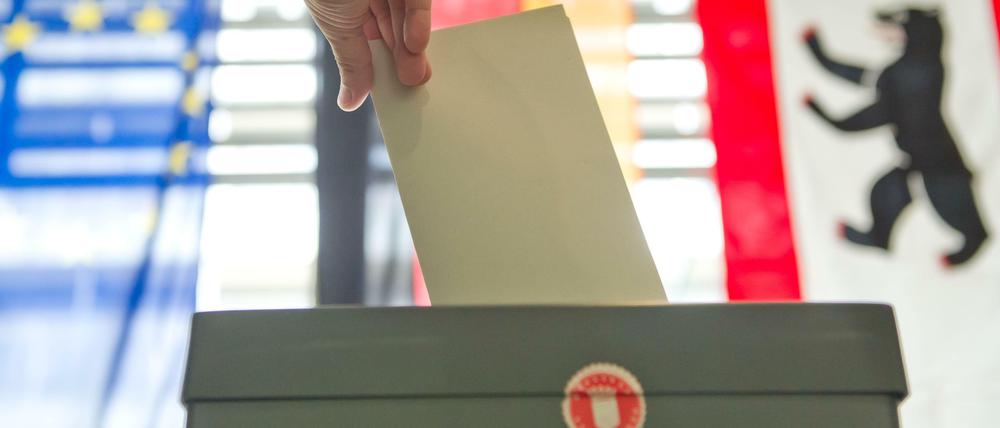 Eine Hand wirft in Berlin bei der Stimmabgabe zur Bundestagswahl einen Stimmzettel in eine Wahlurne.