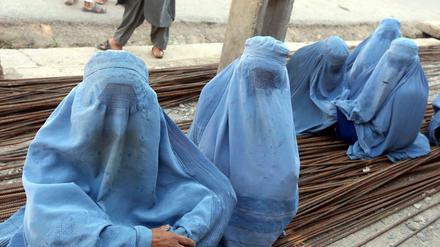 In Burkas gekleidete Frauen sitzen in Herat (Afghanistan) auf Metallstangen.