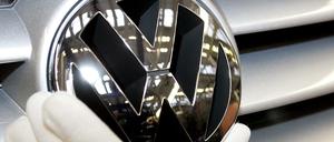 Ein Arbeiter setzt ein VW-Firmenlogo auf einen Golf-Kühlergrill.