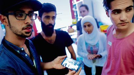 Neuberliner. Syrische Flüchtlinge, die vom Verein „Moabit hilft“ betreut werden, verfolgen die Nachrichten aus ihrer alten Heimat auf einem Smartphone. 