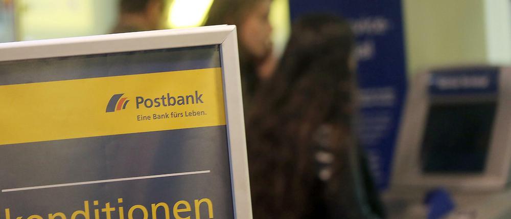 Kunden der Postbank in Köln vor einer Filiale am Geldautomaten.
