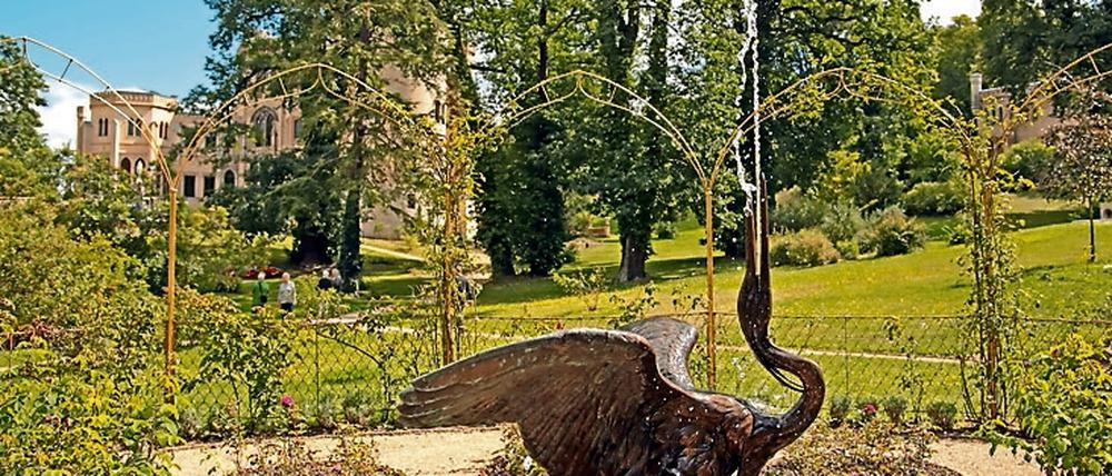 Blick auf ein Wasserspiel und das Schloss.